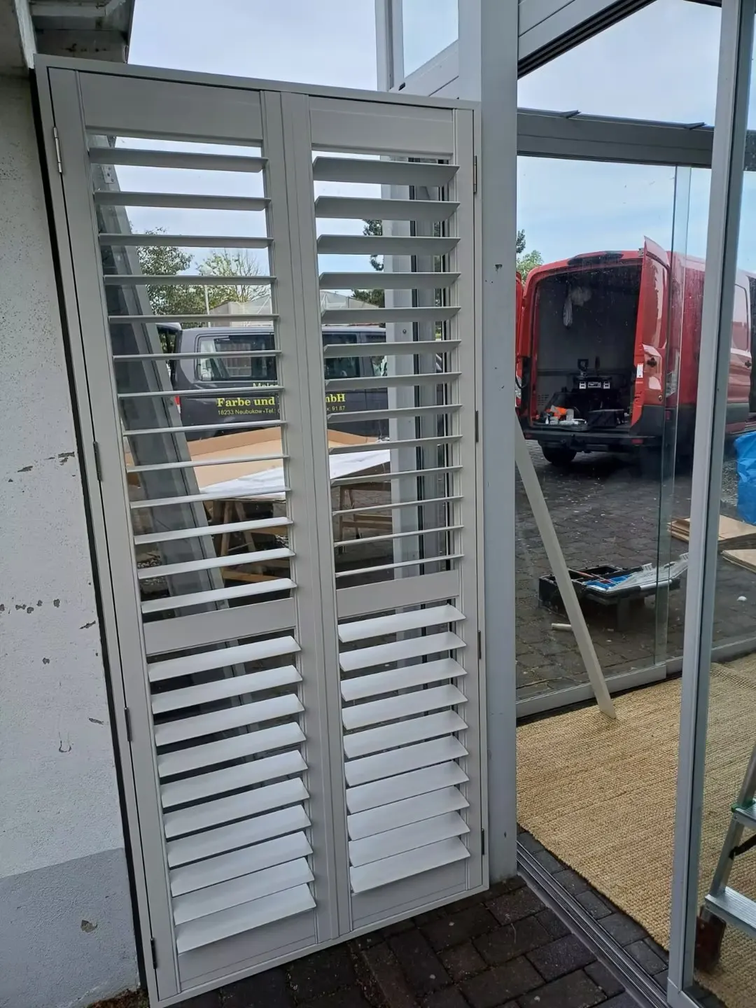 Light grey aluminium shutter panels beside a glass door