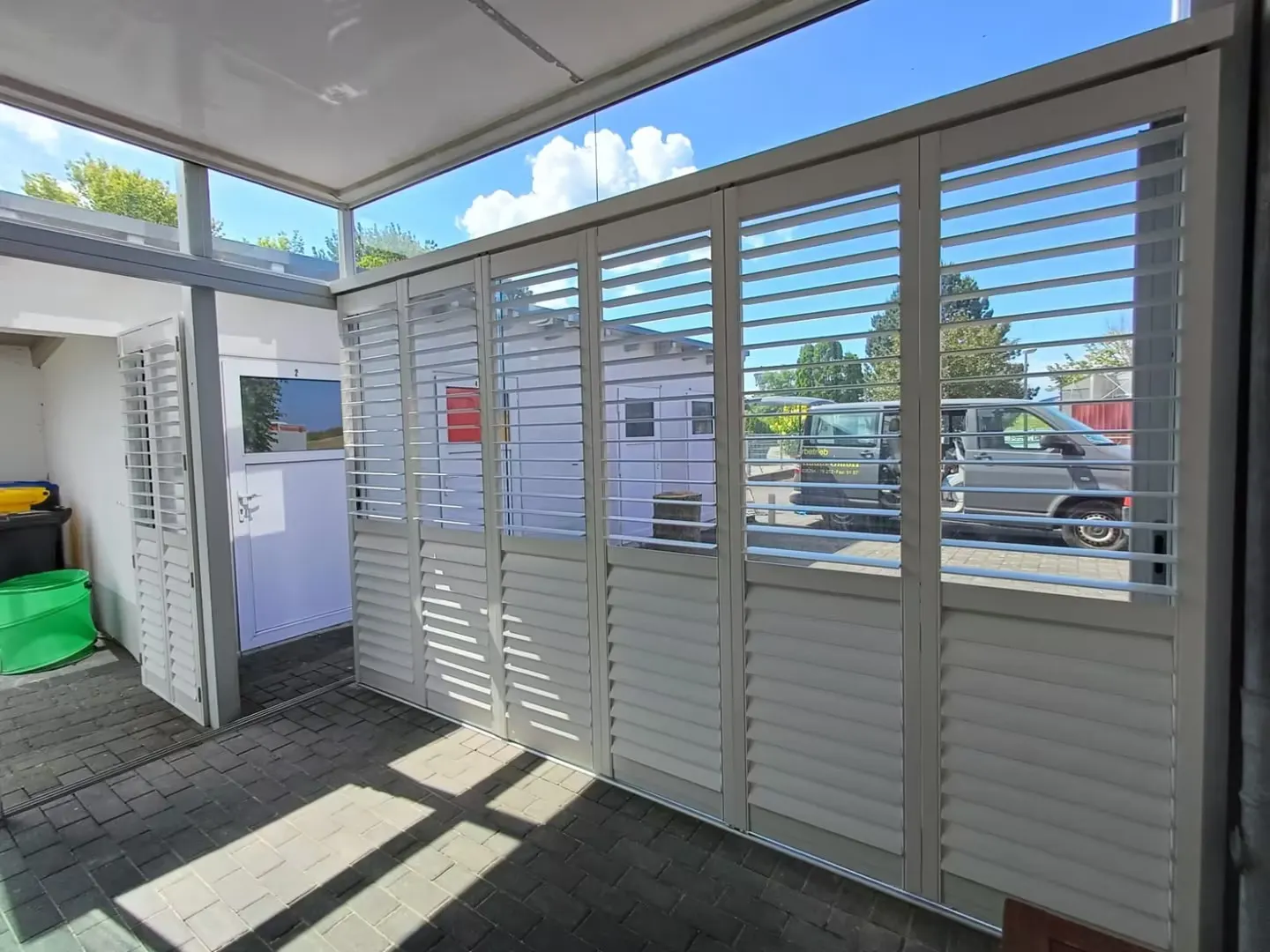 White aluminium shutters with split open and closed louvres on an outdoor track