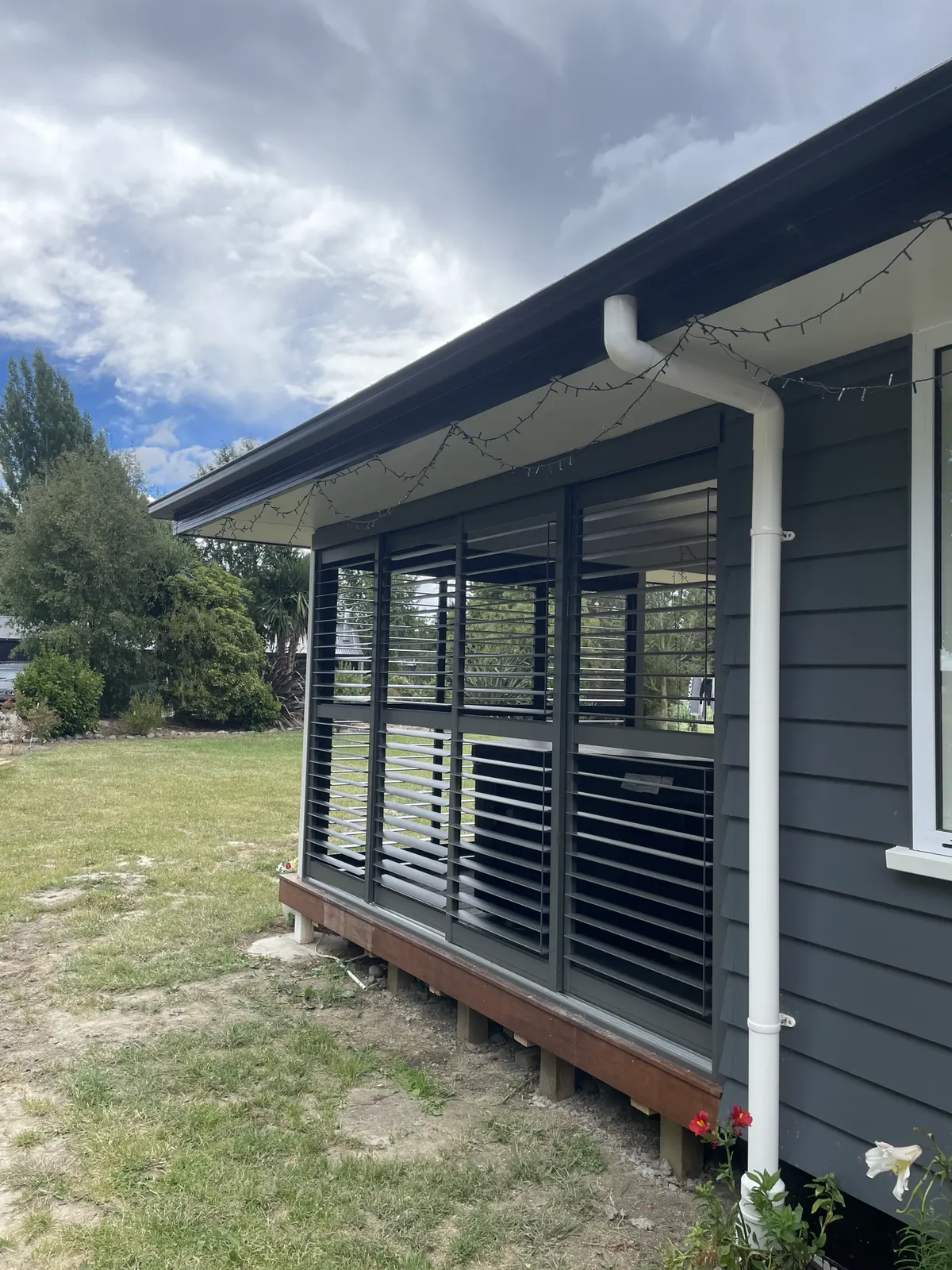 Charcoal aluminium plantation shutters enclosing a timber deck patio