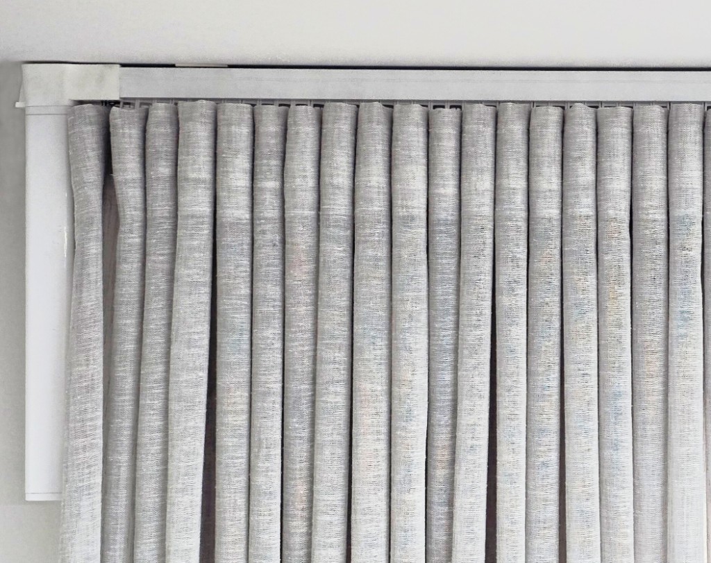 Motorised curtain track with white Novo motor at the ceiling, S-fold sheer curtain gliders